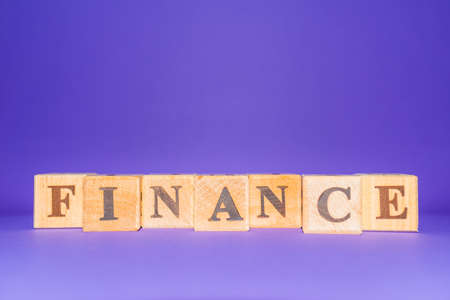 FINANCE word written on wood blocks and number cubes put on purple ,veri peri background.Copy space.の写真素材