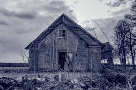Old wooden house,dramatic clouds at night. Abandoned Haunted Horror House.Near is stand trees at evening.Black and white.の写真素材