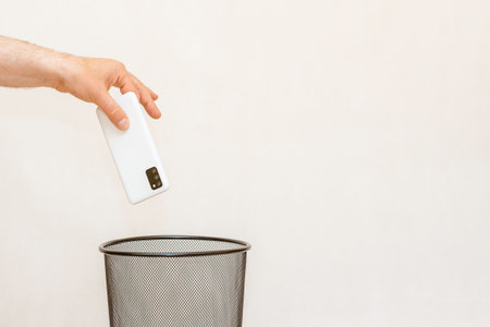 The smartphone is thrown into the trash for disposal and recycling.White,gray background,selective focus,copy space.の写真素材