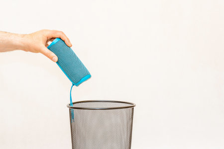 The portable bluetooth speaker is thrown into the trash,can for disposal and recycling.White,gray background,selective focus,copy space.の写真素材