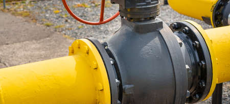 Two black and yellow gas pipes are connected by large bolts.Background for suppliers of gas products and pipes.Close-up,selective focus.Banner,advertisement.の写真素材