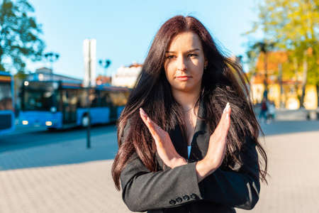 Pretty business woman with her arms crossed at her chest demonstrates break the bias symbol of woman's international day.Woman show solidarity,breaking stereotypes, inequality.sunset city outdoors.の写真素材