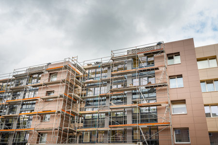 Tall building under construction with scaffolds.Scaffolding on multi storey building facade during renovation.Telsiai,Lithuania 05-31-2022.のeditorial素材
