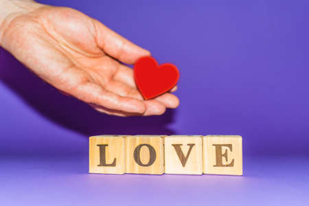 Man palm holding red heart on a veri peri color background,wooden letters love.の写真素材