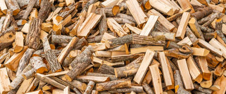 A pile of stacked firewood, prepared for heating the house. Firewood for ready heating in winter.Chopped firewood.environment background.Banner,advertisement.の写真素材