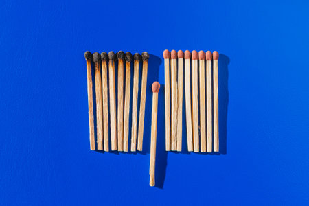 Group of burnt out and unused match sticks on blue background. Save a community concept.の写真素材
