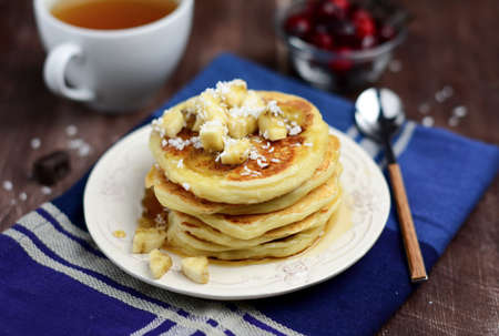 Cottage cheese pancakes with banana, coconut and maple syrup. Morning breakfast tableの写真素材
