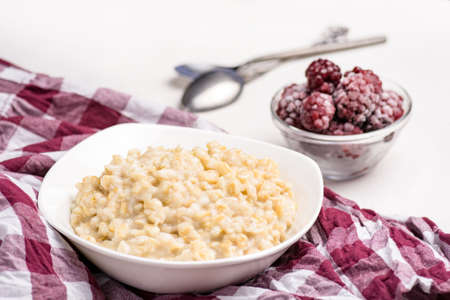 Bowl of oatmeal porridge and frozen blackberries on background. Healthy breakfastの写真素材