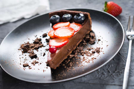 Piece of chocolate pie (cake, tart) decorated with fresh fruits and berriesの写真素材