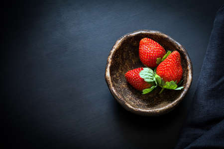 Fresh strawberries in a bowl on black background, top view. Still lifeの写真素材