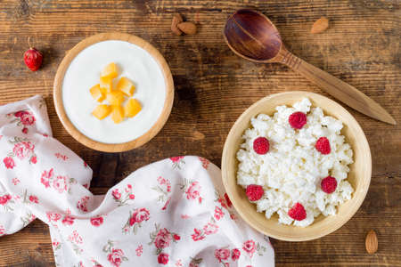 Cottage cheese with raspberry and yogurt with peach on wooden backgroundの写真素材