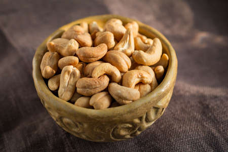 Roasted cashews in a bowl on burlap background. Selective focusの写真素材