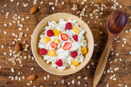 Cottage cheese, yogurt, fruit and berry with muesli in bowl. Healthy breakfast, top viewの写真素材