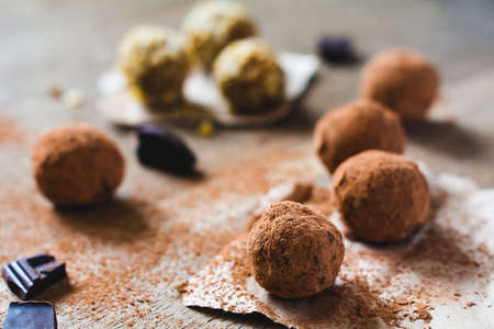 Assorted dark chocolate truffles on parchment paper dusted with cocoa powder. Close up, selective focusの写真素材