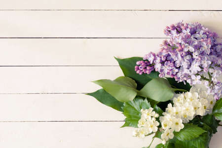 Lilac flowers and white flowers with green leaves on vintage white / yellow wooden background. Copy space for text. Great use for gift cards, post cards, invitation cards and posters.の写真素材