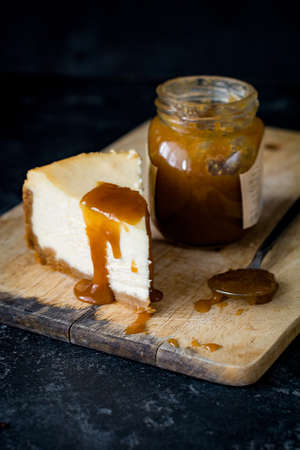Cheesecake with caramel sauce on wooden chopping board. Close up, selective focusの写真素材