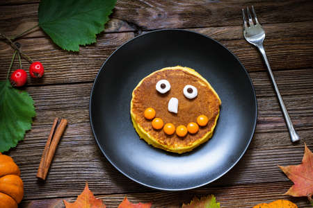 Pumpkin pancakes for kids, creative funny pancakes with smileys on plate. Top viewの写真素材