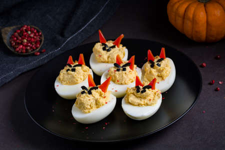 Deviled eggs with funny faces served on black plateの写真素材