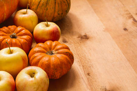 Small pumpkins and apples on wooden table with copy space for text. Autumn harvest, food ingredients for Thanksgiving day. Horizontalの写真素材