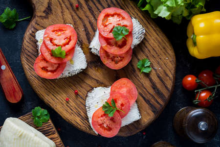 Healthy snack, appetizer: goat cheese and tomato on whole grain rye toast. Top viewの写真素材