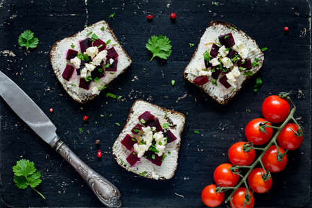 Goat cheese, roasted beet and feta cheese appetizer sandwiches on black cutting board, top viewの写真素材