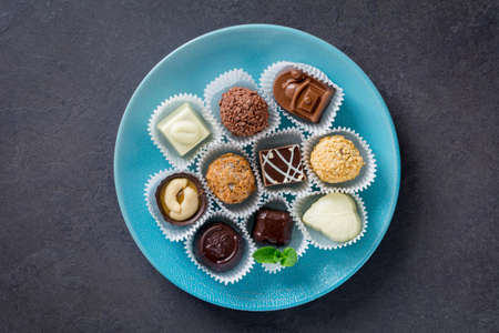 Assortment of fine chocolates on a blue plate. Top viewの写真素材