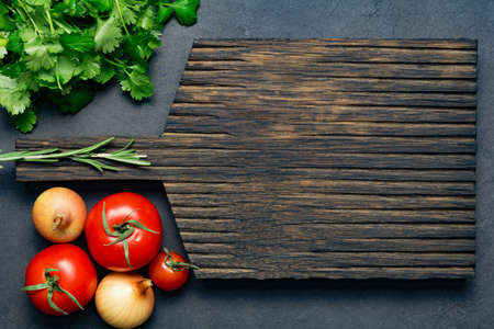 Food background: wooden cutting board, fresh tomatoes, onions and bunch of parsley. Empty space for your text. Top viewの写真素材