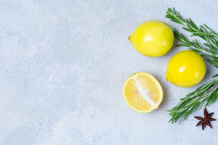 Fresh organic lemons and rosemary on bright blue stone background with copy space for text. Top view. Healthy ingredients for cookingの写真素材