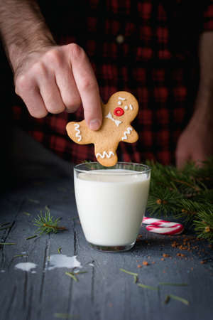 Gingerbread man cookie sinking in a glass of milk. Christmas holidays food, winter and New Year conceptの写真素材
