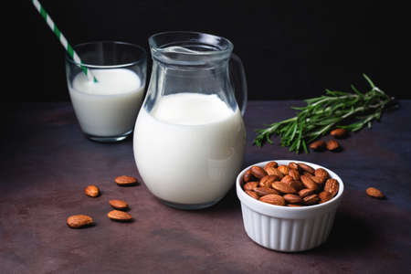 Homemade almond milk on dark rusty background over black background. Dairy free vegan milk. Toned imageの写真素材