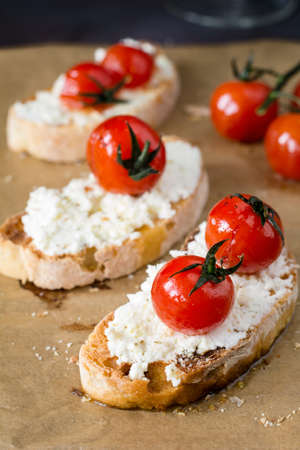 Bruschetta with roasted cherry tomato and fresh ricotta cheese garnished with extra virgin olive oil. Italian cuisine appetizer. Close up viewの写真素材