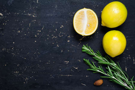 Fresh organic lemons and rosemary springs on textured wooden background with copy space for text. Top view, flat lay. Organic, raw, healthy food backgroud.の写真素材