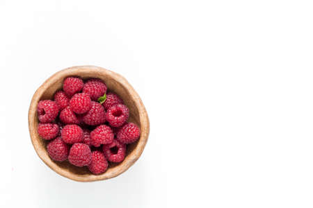 Raspberries in bowl isolated on white, top view