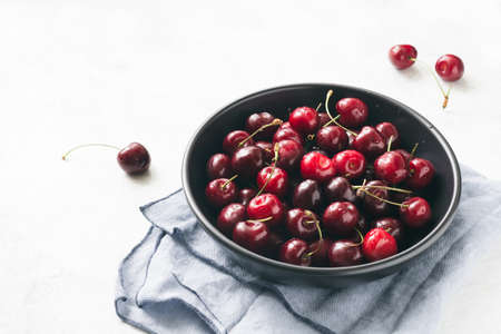 Sweet cherry in black bowl over bright background. Closeup view. High exposureの写真素材