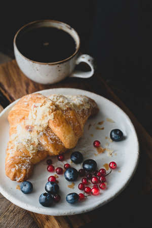 Almond croissant, berries and cup of coffee. Closeup view, toned imageの写真素材