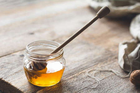 Jar of honey and honey dipper on wooden tableの写真素材