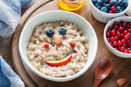 Meal for kids - oatmeal porridge bowl with cute funny face made with fruits. Cozy breakfast foodの写真素材