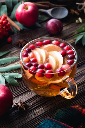 Warming winter berry tea with cranberries, apple, cinnamon, lemon, honey and thyme in a glass cup on...