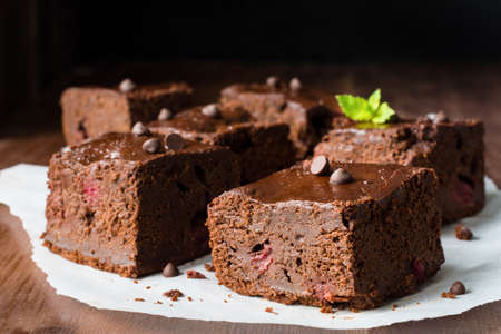 Dark chocolate brownies decorated with mint leaf on wooden table. Closeup view horizontal compositionの写真素材