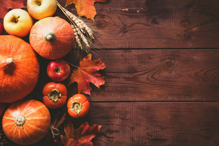 Thanksgiving background: pumpkins, apples, wheat, maple leaves, cones and spices on brown wooden background. Seasonal fall background for Thanksgiving or Halloween. Design mock up. Horizontalの写真素材