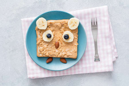Peanut butter toast for kids healthy breakfast in shape of cute owl on a blue plate. Table top viewの写真素材