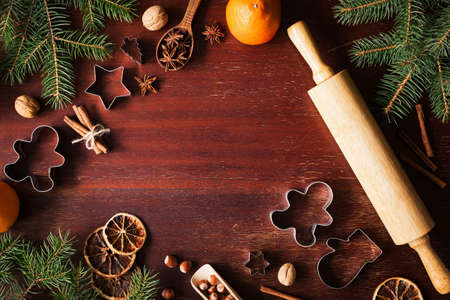Winter holidays Christmas New Year background with cookie cutters, spices, nuts, Christmas tree and Gingerbread cookies on wooden background. Top view copy space for textの写真素材