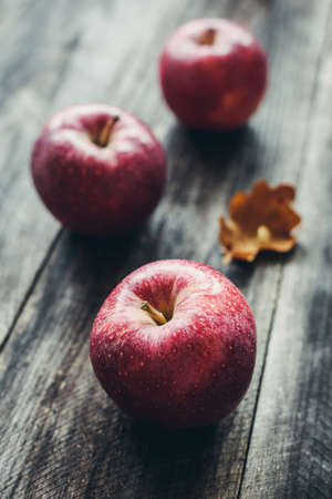Red apples on wooden background. Selective focus. Moody toned autumn applesの写真素材