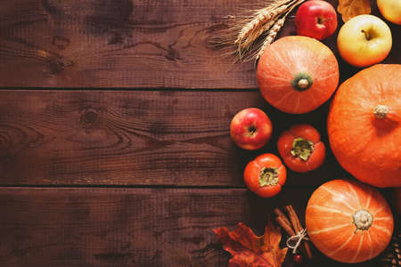 Thanksgiving background: pumpkins, apples, wheat, maple leaves, cones and spices on brown wooden background. Seasonal fall background for Thanksgiving or Halloween. Design mock up. Horizontalの写真素材