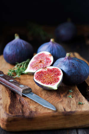 Fresh purple figs cut half on wooden cutting board. Closeup view, selective focusの写真素材