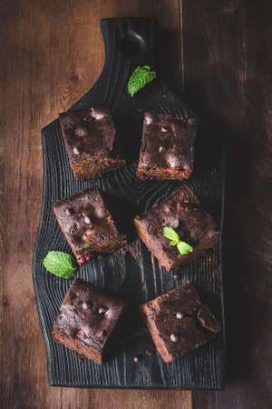 Dark chocolate brownies decorated with mint leaf on dark background. Top view, vertical compositionの写真素材