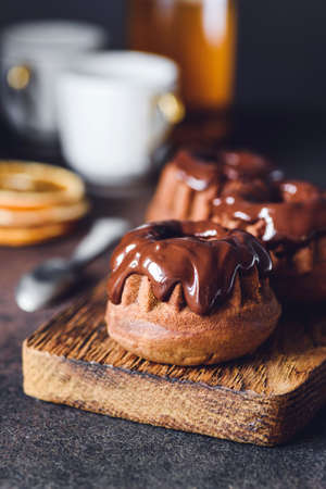 Chocolate mini bundt cakes with chocolate glaze on wooden board. Closeup view, vertical compositionの写真素材