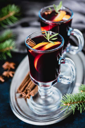 Mulled wine in glass with orange slices, rosemary and cinnamon on silver tray. Traditional holiday drinkの写真素材