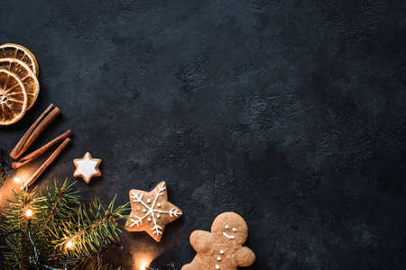 Christmas lights, Gingerbread cookies, Fir tree, Spices and Dried oranges on Dark Stone Background. Winter Holidays Frame Background or Wallpaper with Copy Space. Design mock upの写真素材