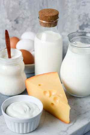Dairy products selection on concrete background. Eggs, Cheese, Milk, Yogurt, Cream and Sour cream. Closeup view, vertical composition